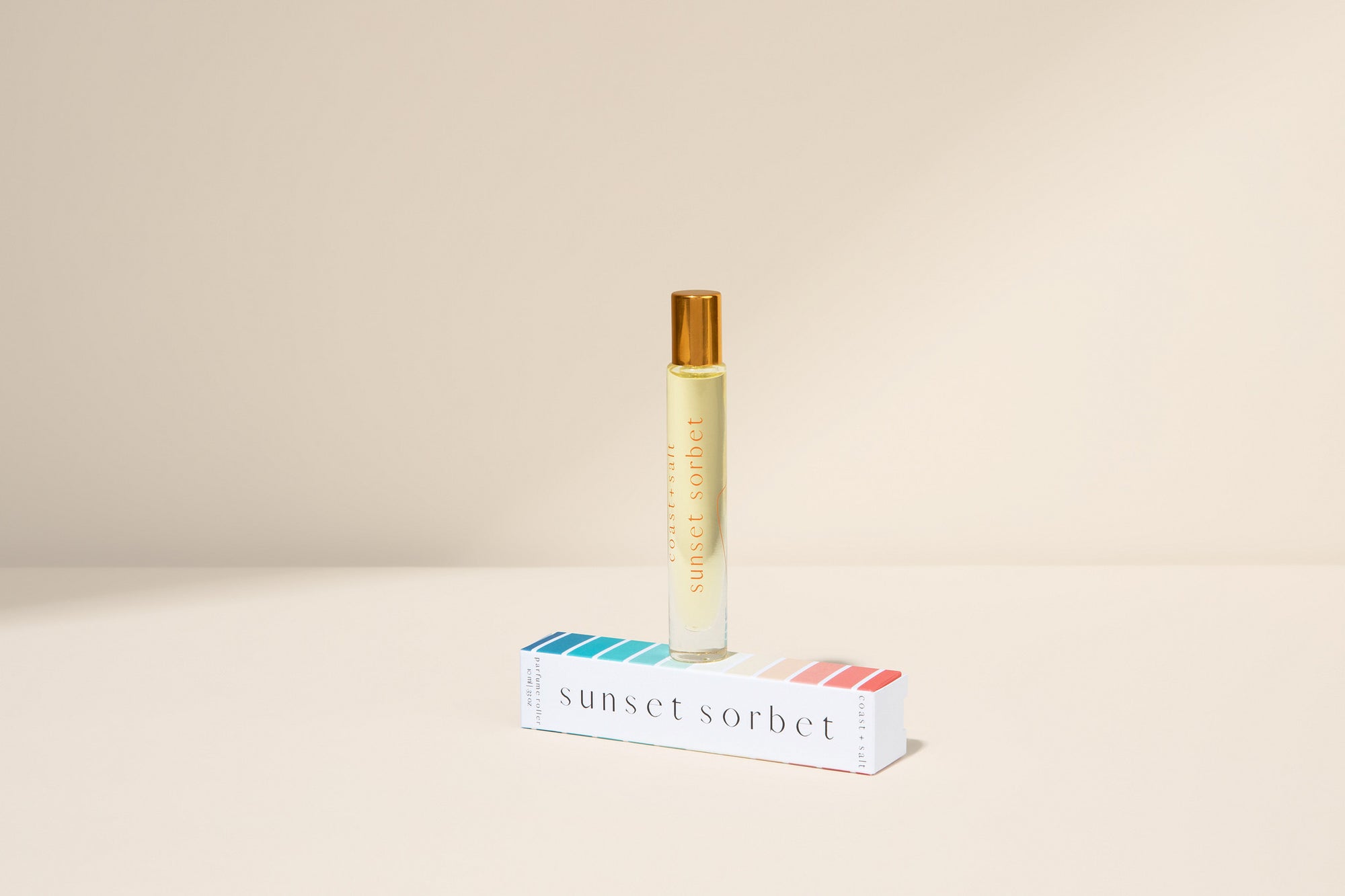 Roll-on bottle of 'Sunset Sorbet' with its packaging on a beige background