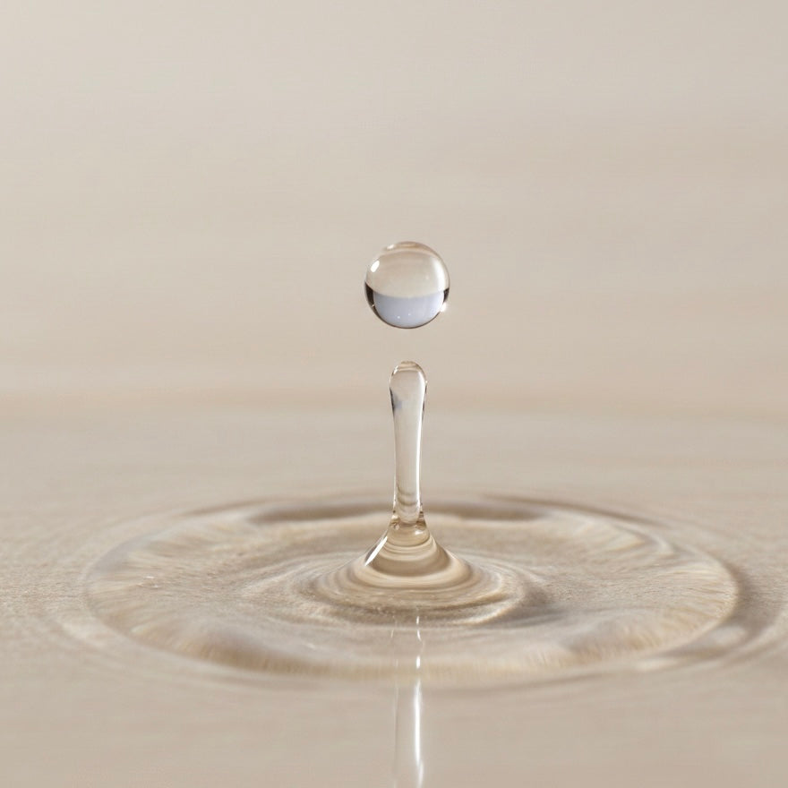 Drop of oil descending into a puddle on a beige background