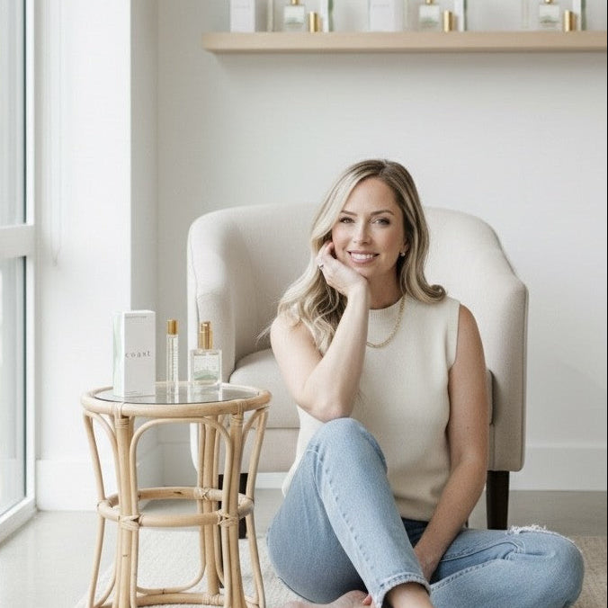 Woman sitting on the floor in front of a chair in a modern room with shelves and decor.