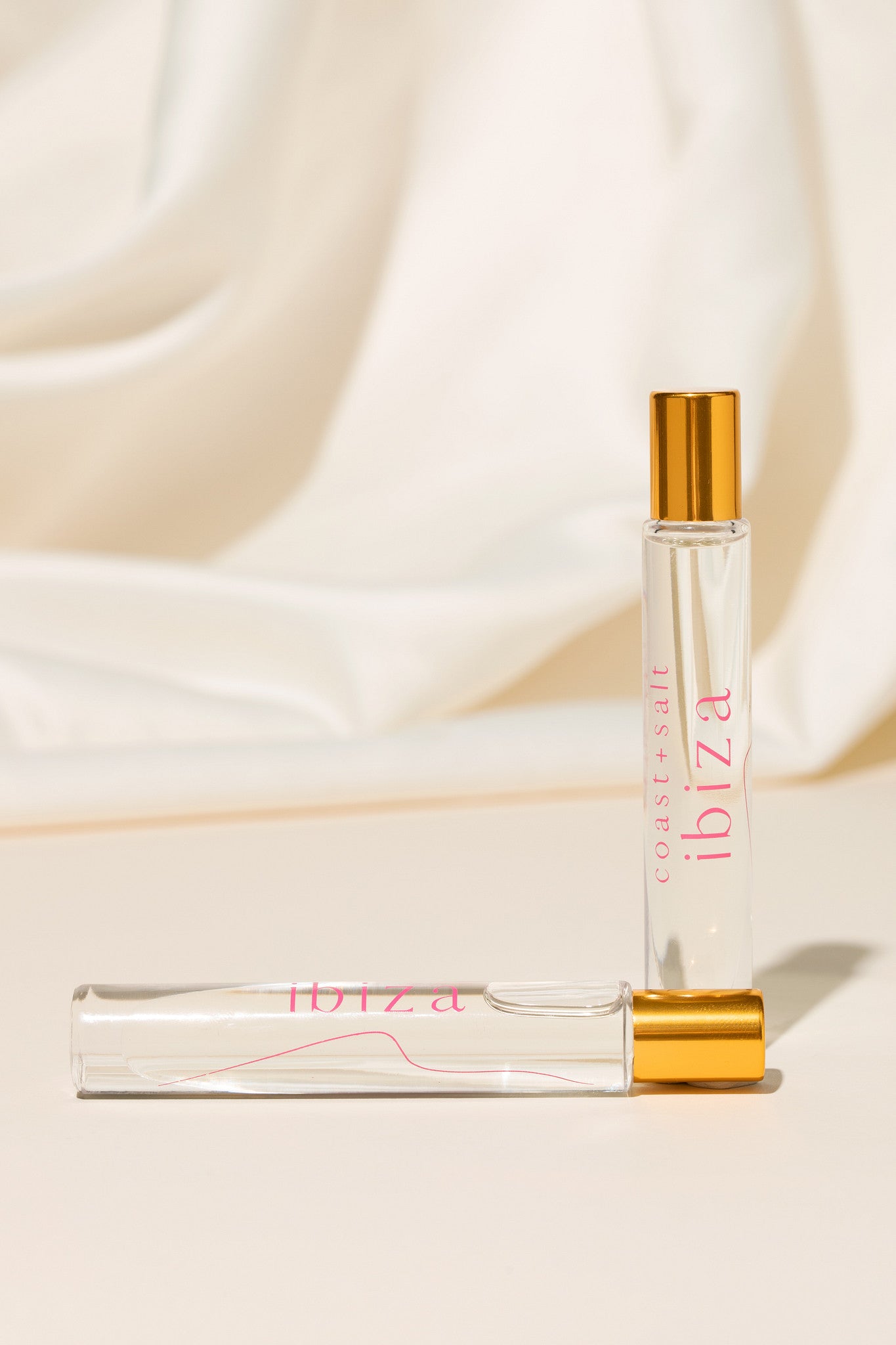 Two roller perfume bottles labeled 'ibiza' on a beige fabric background