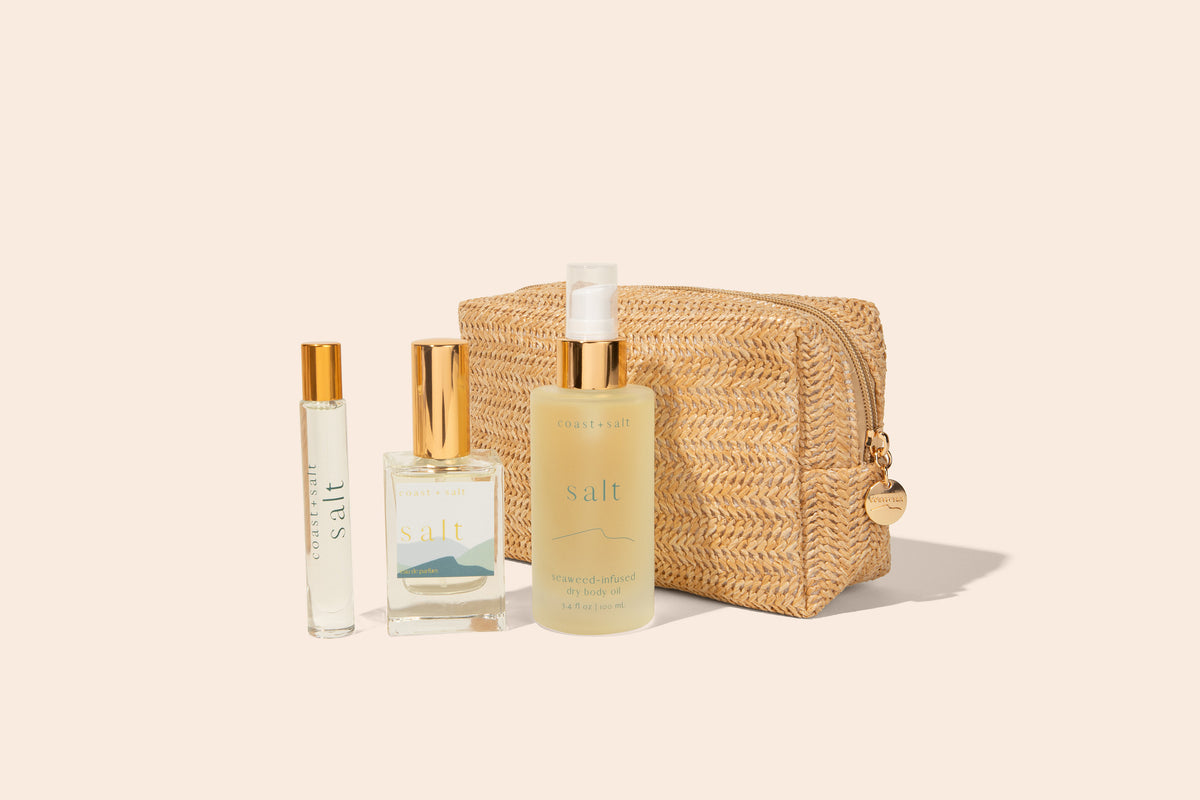 Coast+Salt Salt fragrance gift set featuring a perfume roller, 50 mL eau de parfum, seaweed-infused dry body oil, and natural woven Daytrip Pouch on a beige background.