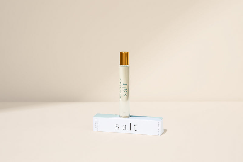 Salt perfume roller standing on a Salt retail packaging box on a neutral background