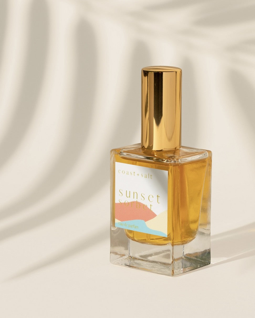 Sunset Sorbet perfume bottle on a beige background with a palm leaf shadow in background