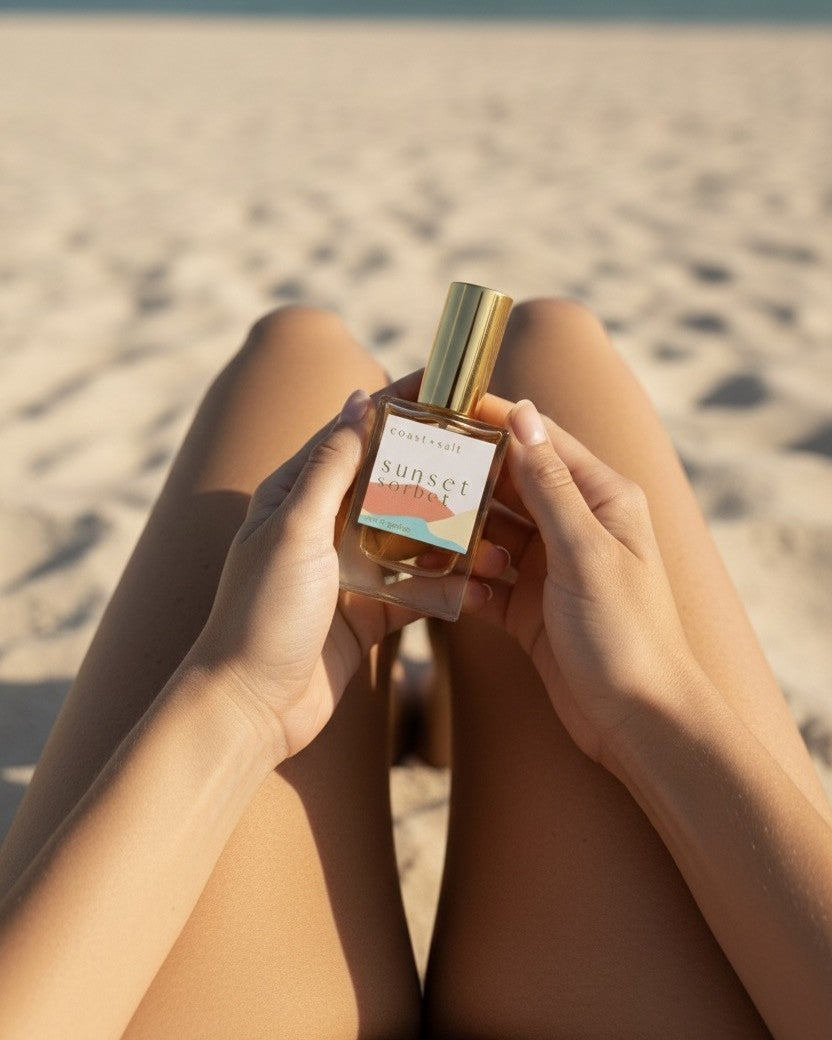 Person holding a Sunset Sorbet perfume bottle on a beach